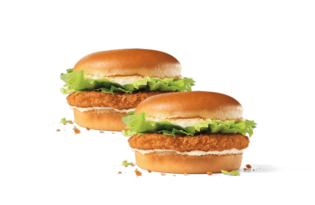 Two crispy junior chicken sandwiches featuring golden-brown breaded chicken patties, fresh green lettuce, and creamy mayonnaise on soft buns, set against a transparent background.
