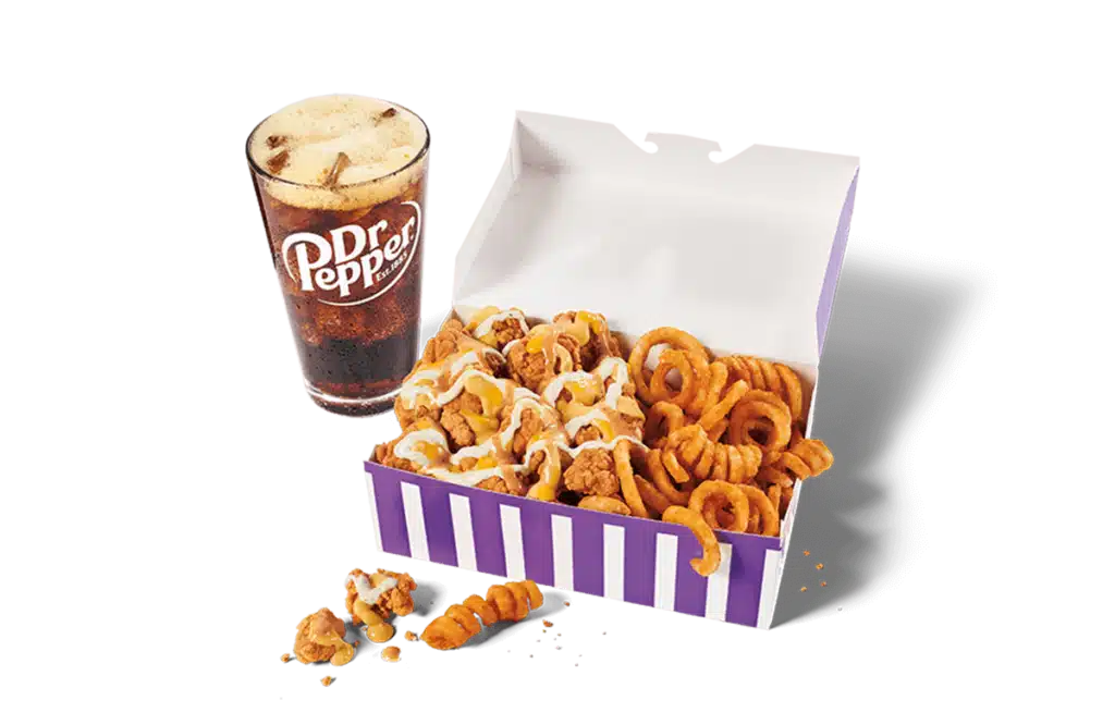 A generous portion of classic sauced & loaded popcorn chicken in a vibrant purple and white box, covered with creamy sauce and paired with crispy curly fries. Next to it is a tall glass of Dr Pepper with foam on top, all set against a clear background.