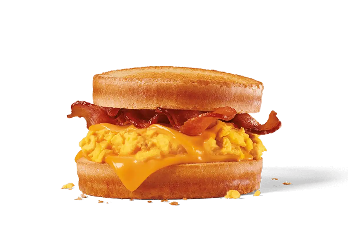 Image of a Bacon, Egg & Cheese Scrambler featuring fluffy scrambled eggs, slices of crispy bacon, and a generous helping of melted cheese, all sandwiched between two lightly toasted English muffins, with crumbs scattered around indicating a fresh, hearty meal.