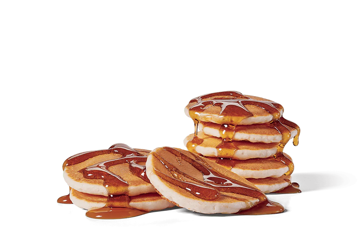 Image of a stack of mini pancakes generously drizzled with maple syrup, creating a tempting, glossy finish over the fluffy, golden-brown pancakes.