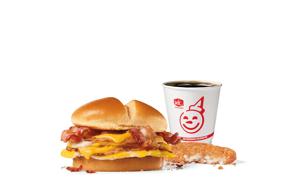 A delectable Ultimate Breakfast Sandwich Combo from Jack in the Box featuring a sandwich with layers of bacon, ham, egg, and melted American cheese on a toasted bun. This combo includes a crispy hash brown and a hot coffee in a branded cup, all against a transparent background.