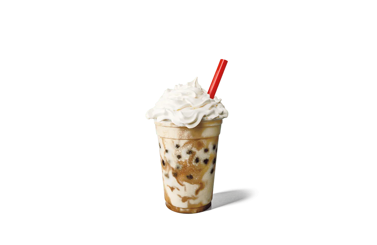 A refreshing vanilla shake speckled with dark boba pearls, served in a clear cup and topped with a lavish swirl of whipped cream. A red straw accents the creamy texture, set against transparent background that enhances the drink's visual appeal.