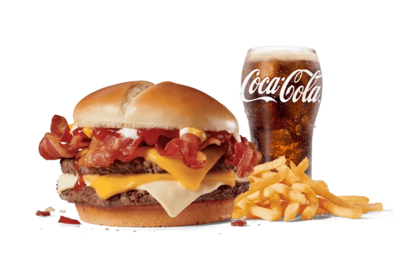A Bacon Ultimate Cheeseburger™ featuring two beef patties, multiple slices of crispy bacon, cheese, and a dollop of sauce, served with a side of fries and a glass of Coca-Cola on transparent background.