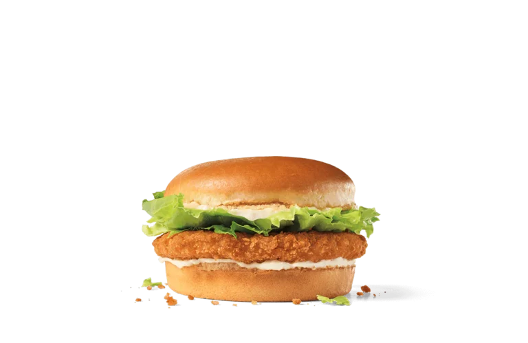 A classic crispy chicken sandwich featuring a crunchy breaded chicken patty, fresh green lettuce, and a soft, golden bun, showcased on transparent background with scattered crumbs around the sandwich.
