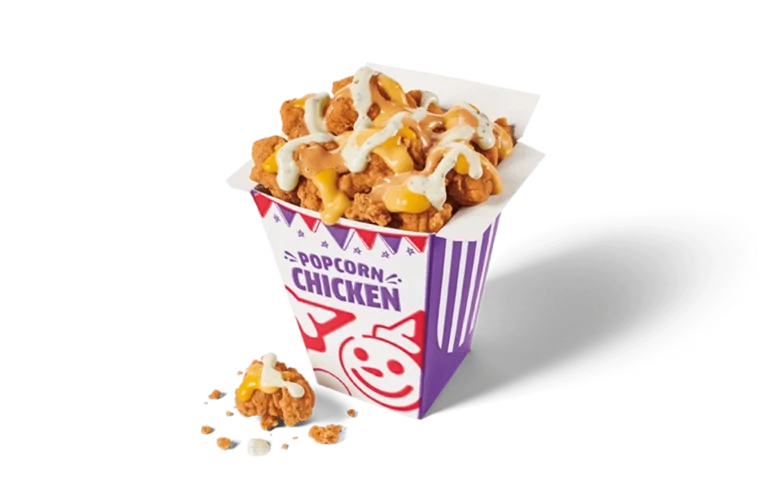 A fun and colorful carton brimming with popcorn chicken drizzled with creamy white and tangy yellow sauces. The crispy chicken pieces are nestled tightly together, showcased in a white and purple striped carton with playful designs, scattered with crumbs on transparent background.