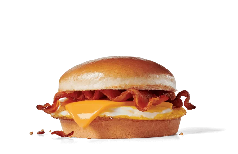 Image of a Bacon Breakfast Jack® sandwich, showcasing a golden, fried egg topped with a slice of melty American cheese and several strips of crispy bacon, all nestled within a soft, shiny hamburger bun.