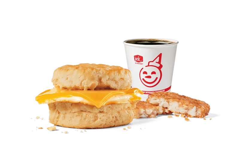 A simple yet satisfying breakfast combo from Jack in the Box featuring a biscuit sandwich with a fried egg and melted cheese, accompanied by a hash brown patty and a cup of hot coffee, presented on a transparent background with the restaurant's iconic smiling logo on the cup.