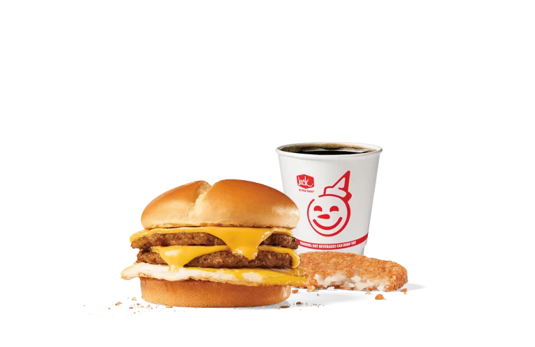 A tantalizing image of the Extreme Sausage® Sandwich Combo from Jack in the Box. The combo includes a hearty sandwich stacked with two sausage patties, egg, and melted cheese on a toasted bun, accompanied by a hash brown and a cup of hot coffee, all set against a simple, transparent background.