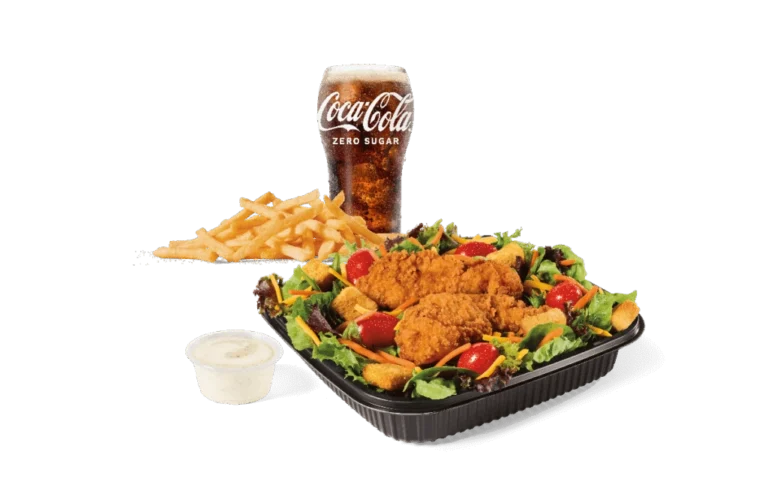 A garden salad topped with crispy chicken strips, served with fries, a cup of ranch dressing, and a Coca-Cola Zero Sugar drink.