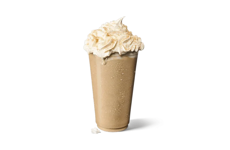 A tall glass of Iced Churro Creamaccino, featuring a creamy coffee base with a frosty texture. The drink is topped with a generous swirl of whipped cream dusted with cinnamon, capturing the essence of churro flavors. Small droplets of condensation on the glass highlight its chilled nature, set against transparent background for an appetizing presentation.