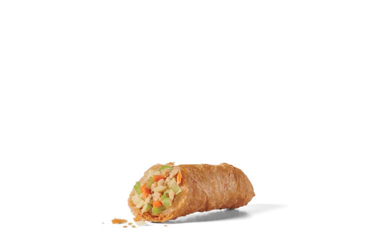 A close-up of a half-sliced jumbo egg roll on transparent background, revealing a filling of finely chopped vegetables including cabbage, carrots, and celery. The egg roll is golden-brown with a crispy, bubbly exterior, and small crumbs are visible around it, suggesting its crunchy texture.