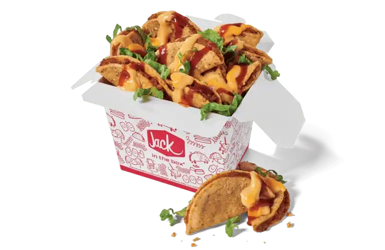 A box of Loaded Tiny Tacos from Jack in the Box. The tacos are served in a white box decorated with red illustrations and the Jack in the Box logo. Each taco is filled with seasoned meat, topped with melted cheese, a drizzle of taco sauce, and fresh shredded lettuce. A few tacos are spilling out of the box for an appetizing display against a transparent background.