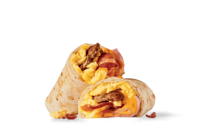 A breakfast burrito cut in half to reveal a filling of scrambled eggs, crispy bacon strips, sausage, and melted cheese, all wrapped in a toasted flour tortilla against a transparent background.