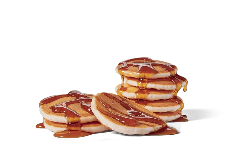 Image of a stack of mini pancakes generously drizzled with maple syrup, creating a tempting, glossy finish over the fluffy, golden-brown pancakes.