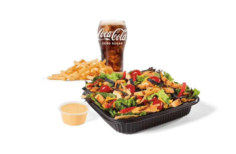 A Southwest salad topped with grilled chicken slices, served with fries, a cup of creamy dressing, and a Coca-Cola Zero Sugar drink.