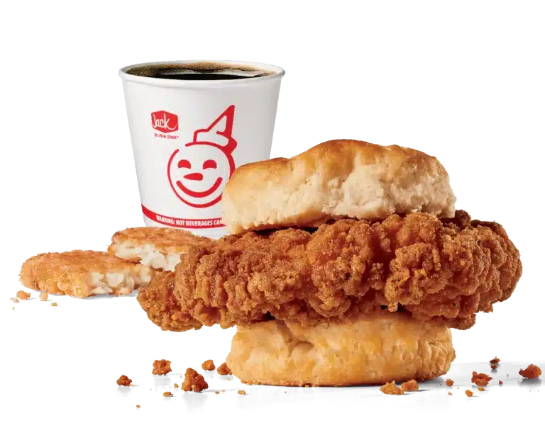 Image showing Jack in the Box's Spicy Chicken Biscuit Combo, which includes a spicy, crispy chicken fillet served on a soft biscuit, paired with a golden hash brown and a white coffee cup featuring the smiling Jack in the Box logo. The meal is highlighted against a transparent backdrop, emphasizing the textures of the flaky biscuit and crunchy chicken.